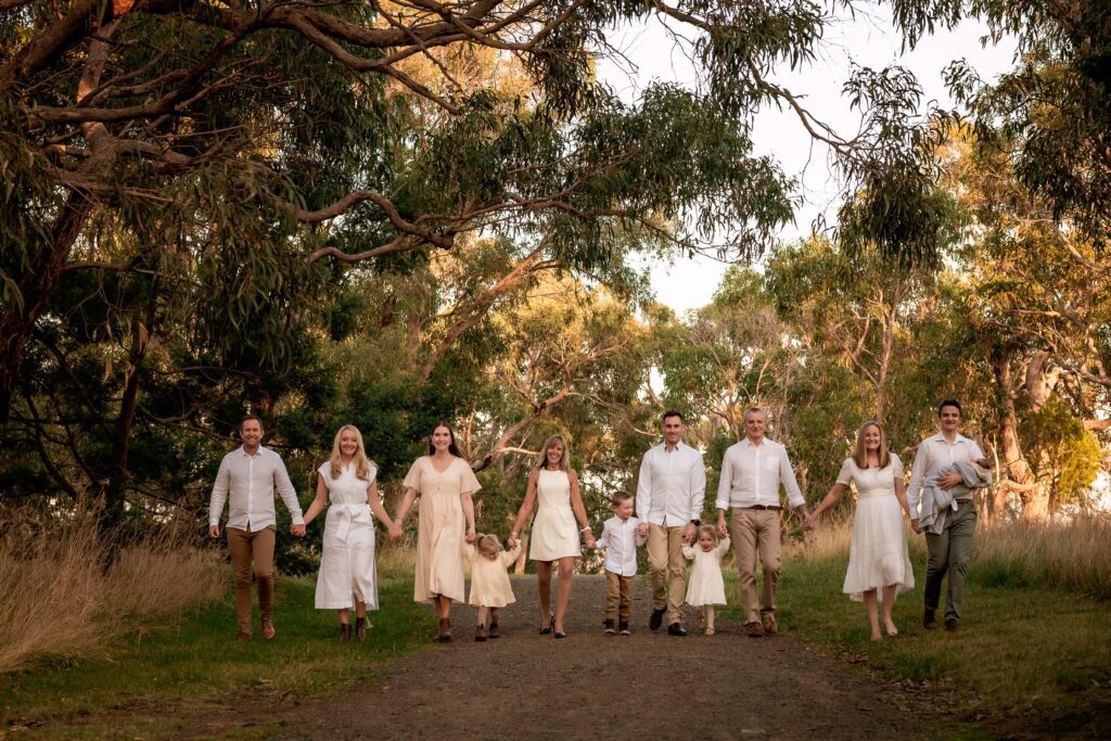 Extended family dressed in cream and white walking towards camera at dusk