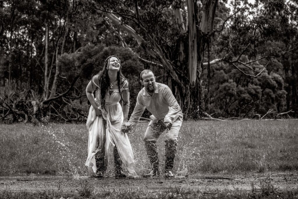 Bride and groom jumping in muddy puddles at forest wedding in the Dandenongs