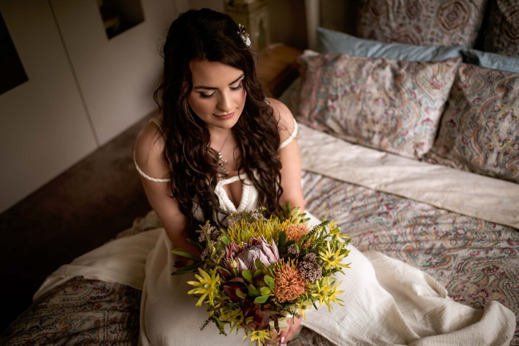 Bridal portrait taken on bed with bride looking down at her flowers
