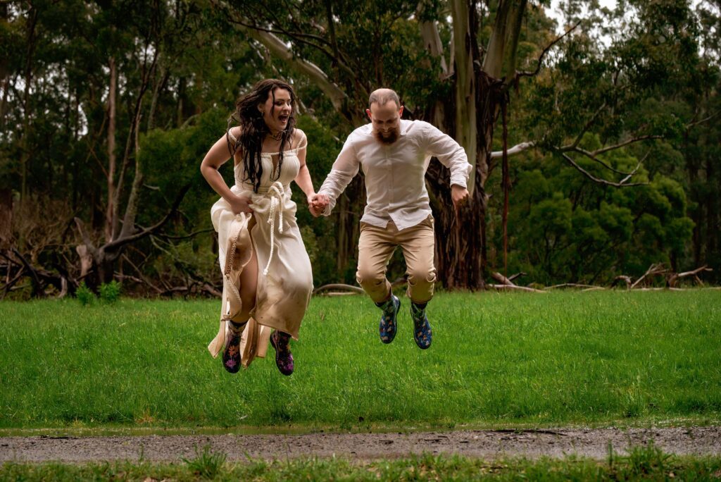 Bride and groom jumping in muddy puddles at forest wedding in the Dandenongs
