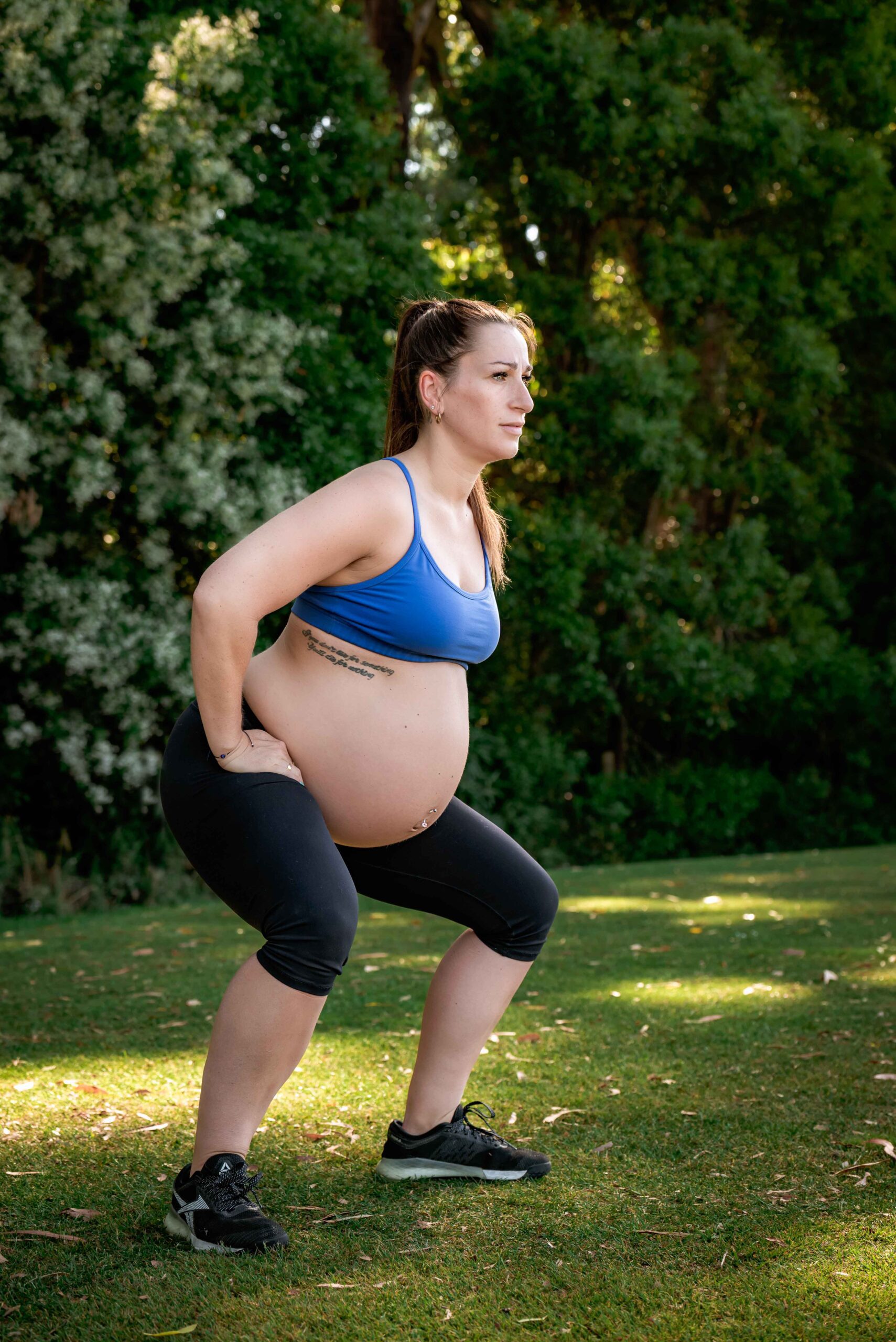 Pregnant mother in blue crop top performing a squat
