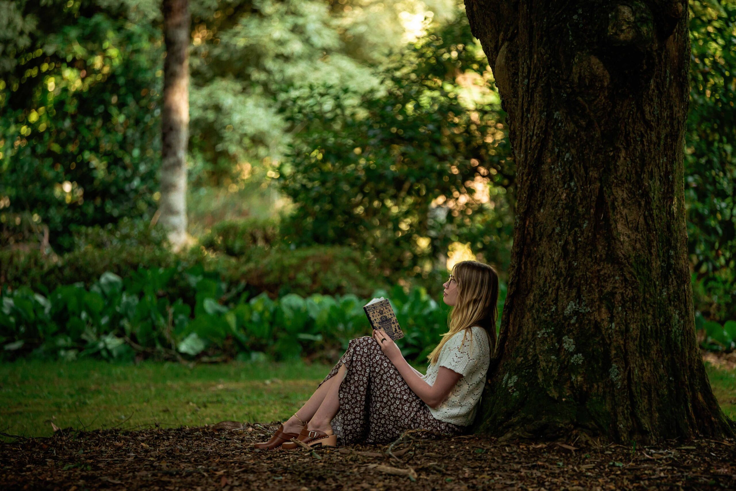 Naturopath sitting under a tree with her journal.