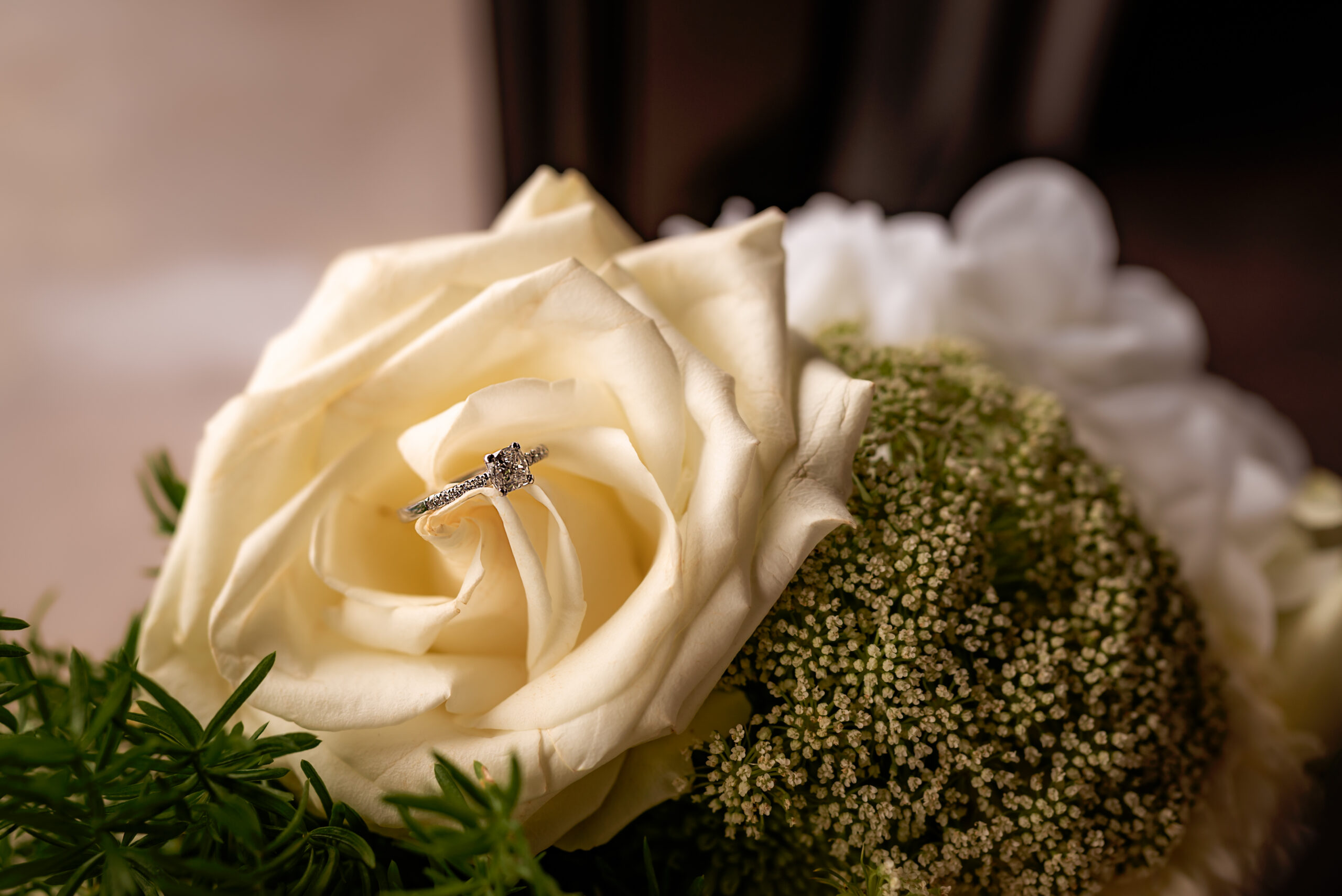 Close up image of engagement ring balanced within bride's bouquet