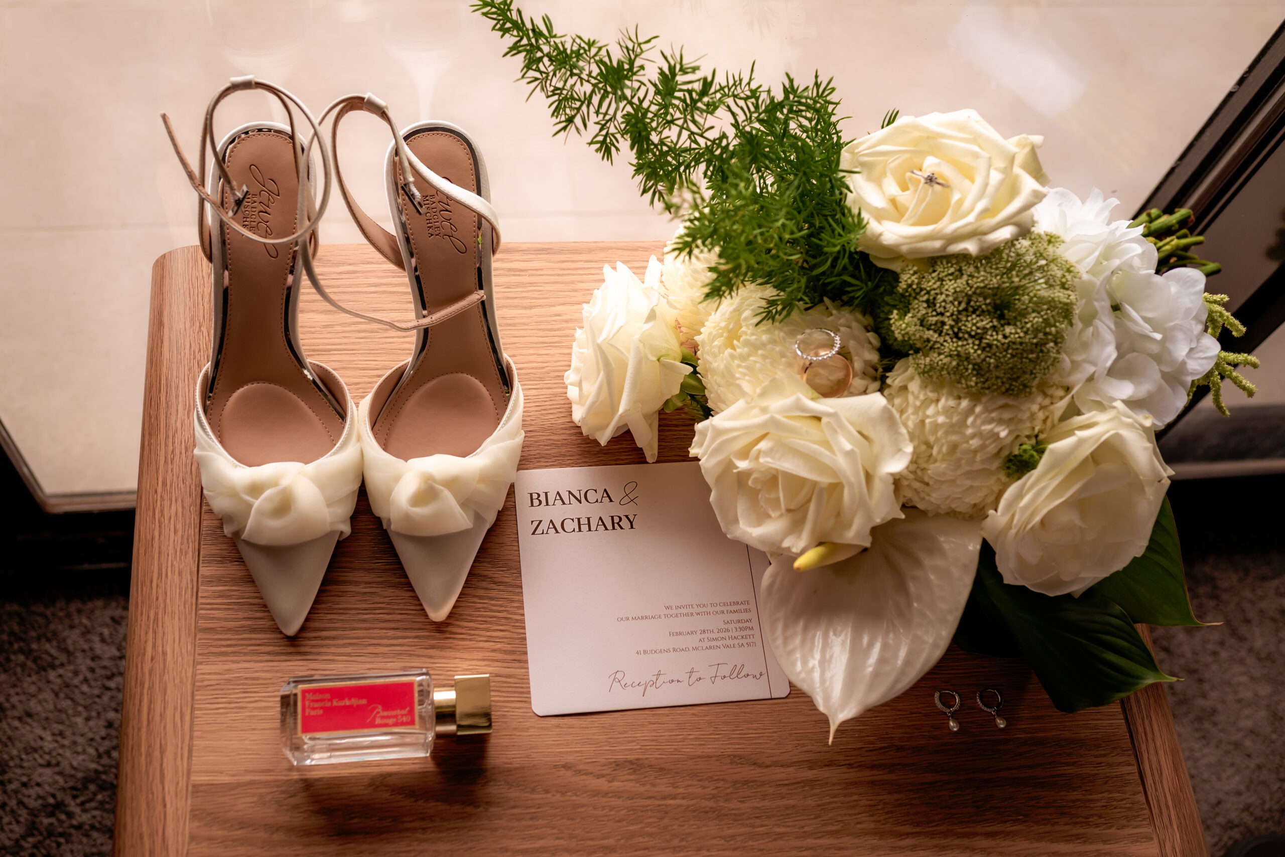 Bridal flat lay including shoes, flowers, invitation and perfume